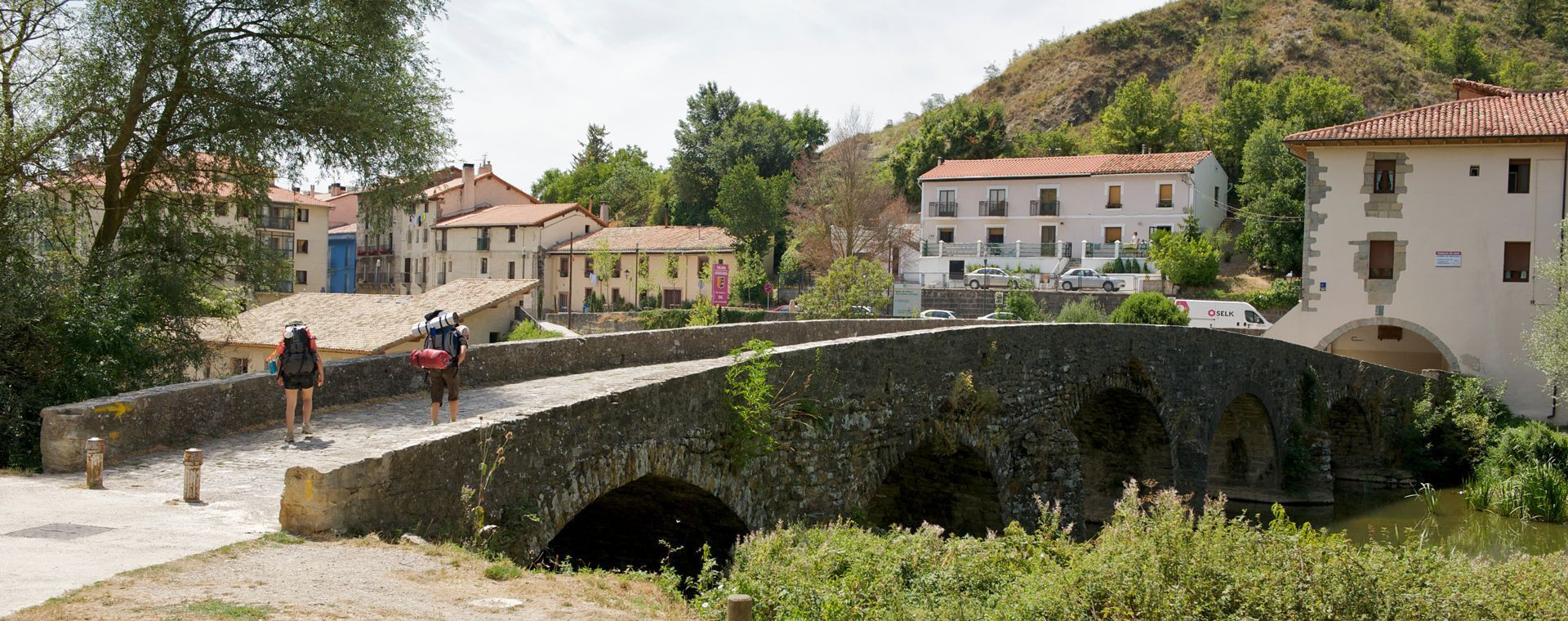 Pilgrims on a medieval bridge - Camino de Santiago - Navarre - Spain
