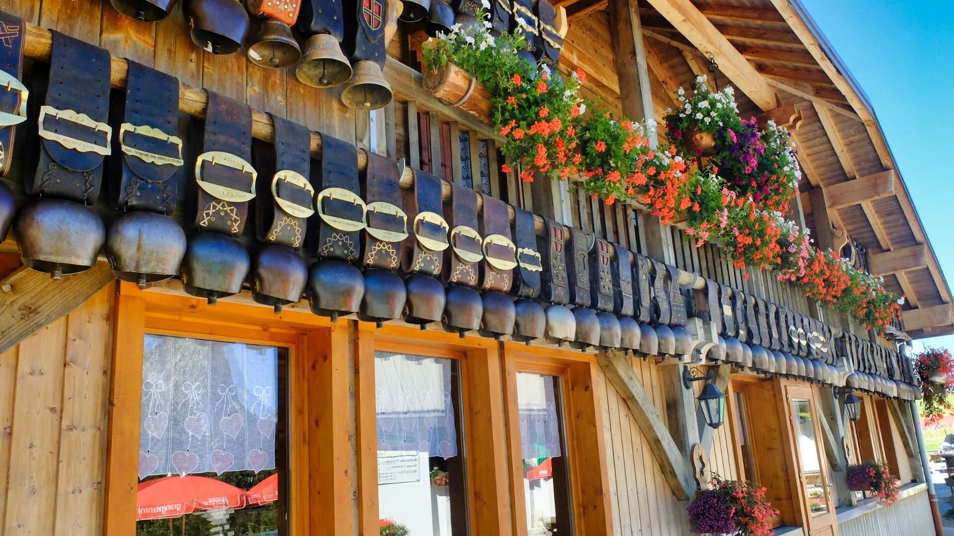 Façade de chalet ornée de cloches et géraniums - Aravis - France