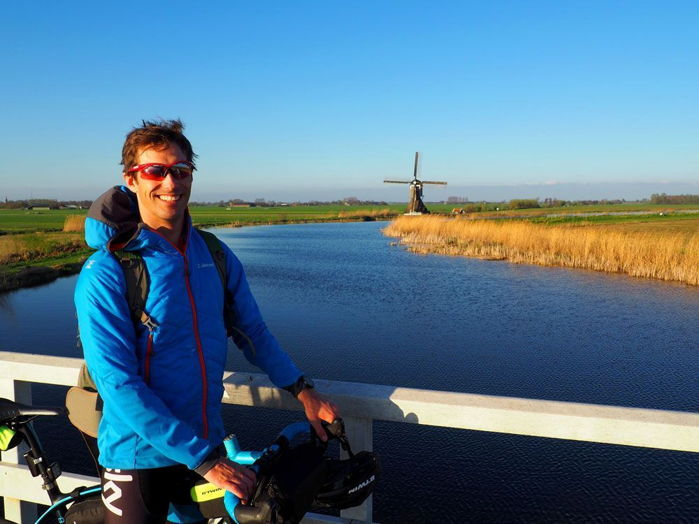 Cycling past a windmill in Kinderdijk in the Netherlands © David Praire