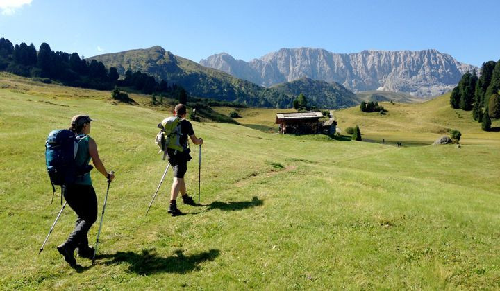 Hikers on a meadow toward the peaks - Dolomites - Italy