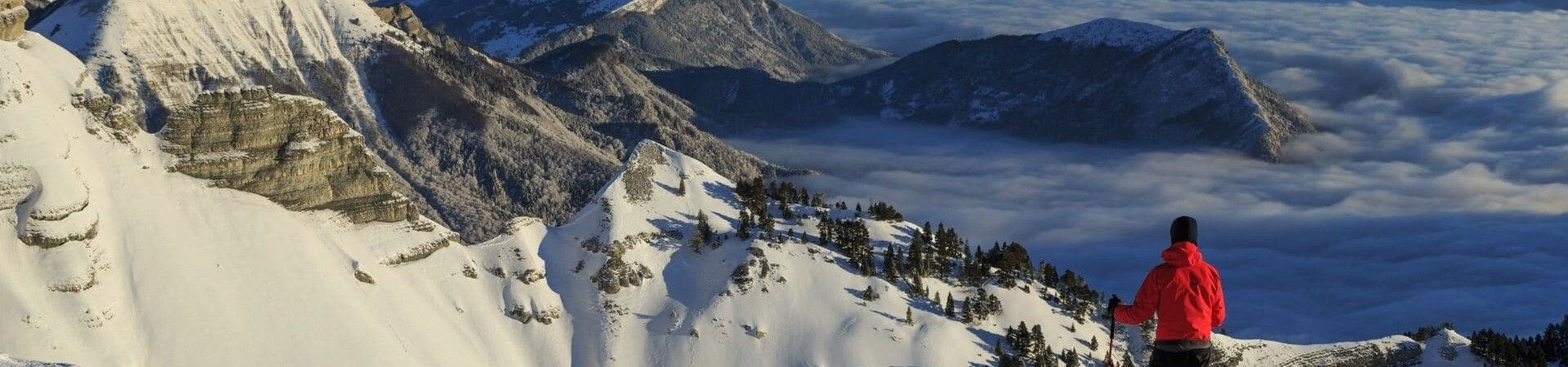 Hiker contemplating snowy peaks above a sea of clouds - Vercors - France