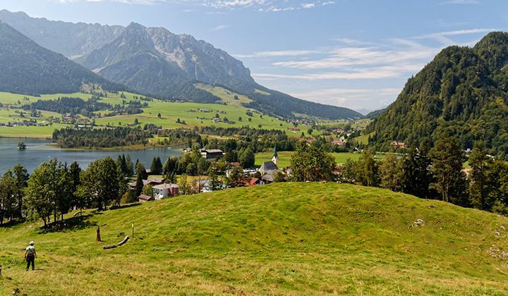 Hiker in an alpine valley with lake and village - Kaisergebirge - Tyrol - Austria