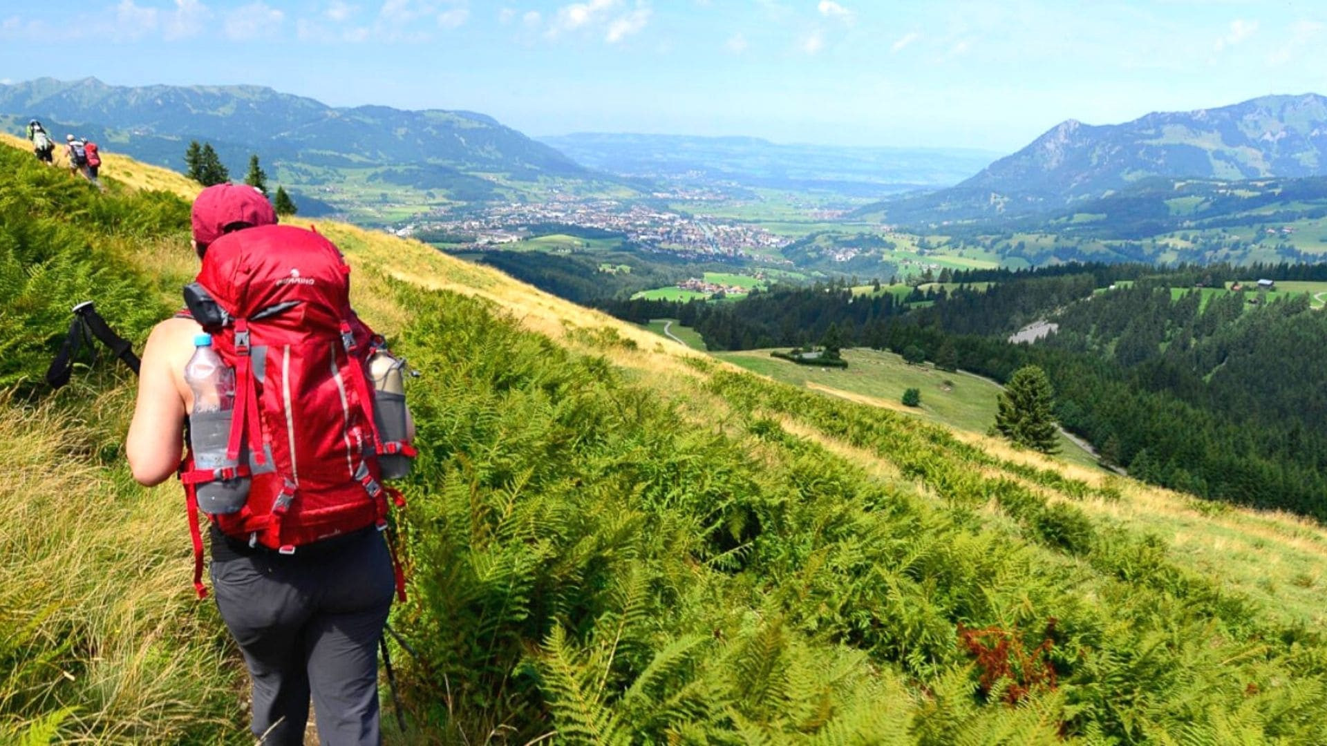 Hiker on a green ridge with valley view - Bavarian Alps