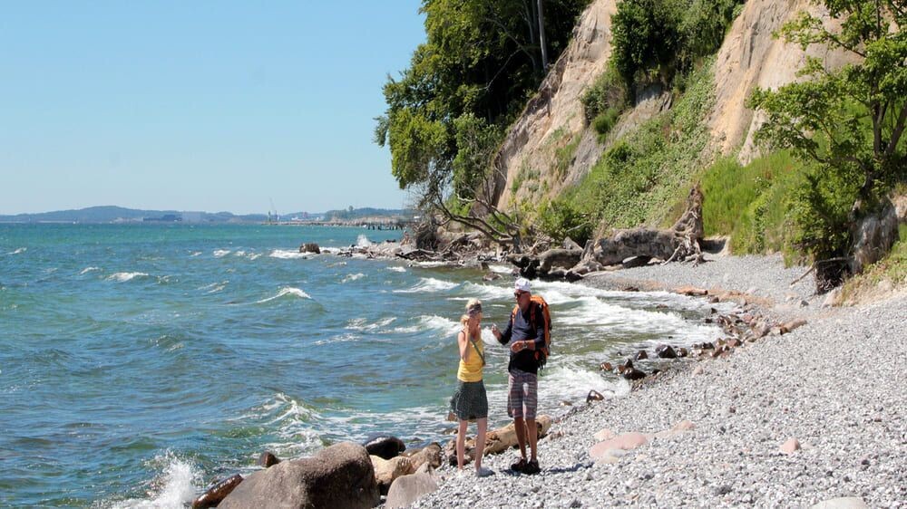 Hikers on the pebble beach below the cliffs - Rügen Island - Baltic Sea, Germany