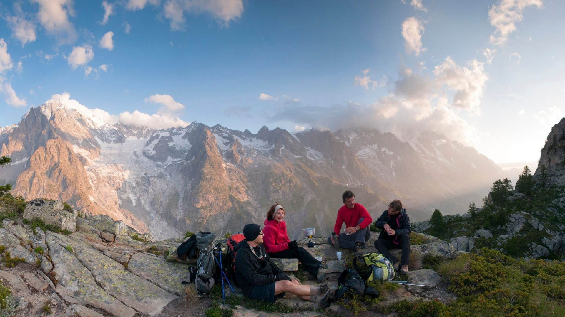 © Jean-Marc Porté Randonneurs en pique-nique face au massif glaciaire au coucher du soleil - Alpes - France