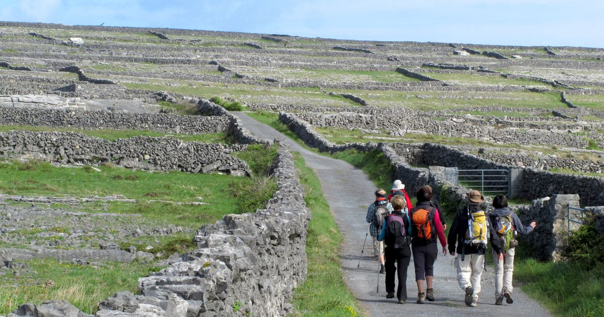 Hikers walking between stone walls - Aran Islands - Ireland