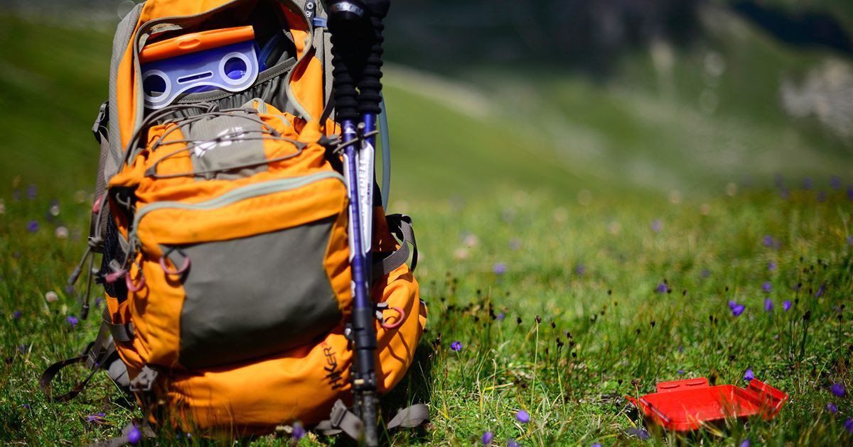 Hiking backpack and poles set on a mountain meadow - Alps