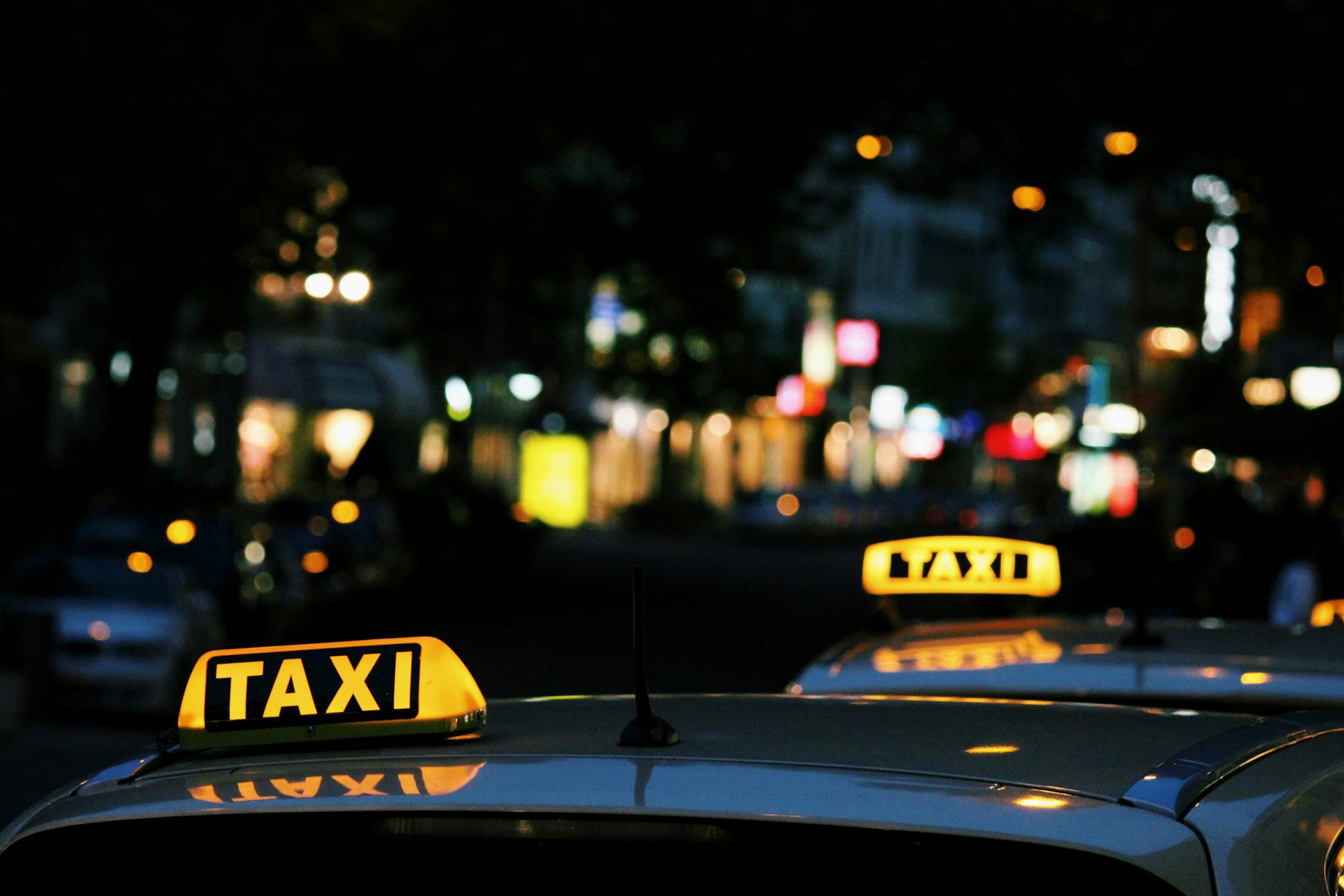 Illuminated taxi roof signs on a street at night