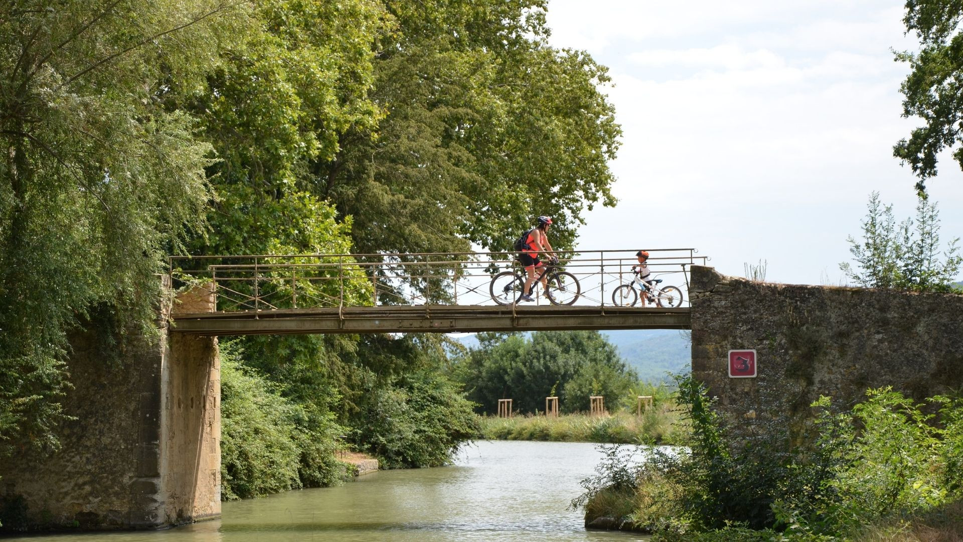 Cyclists crossing a bridge over the Canal du Midi - Occitania - France