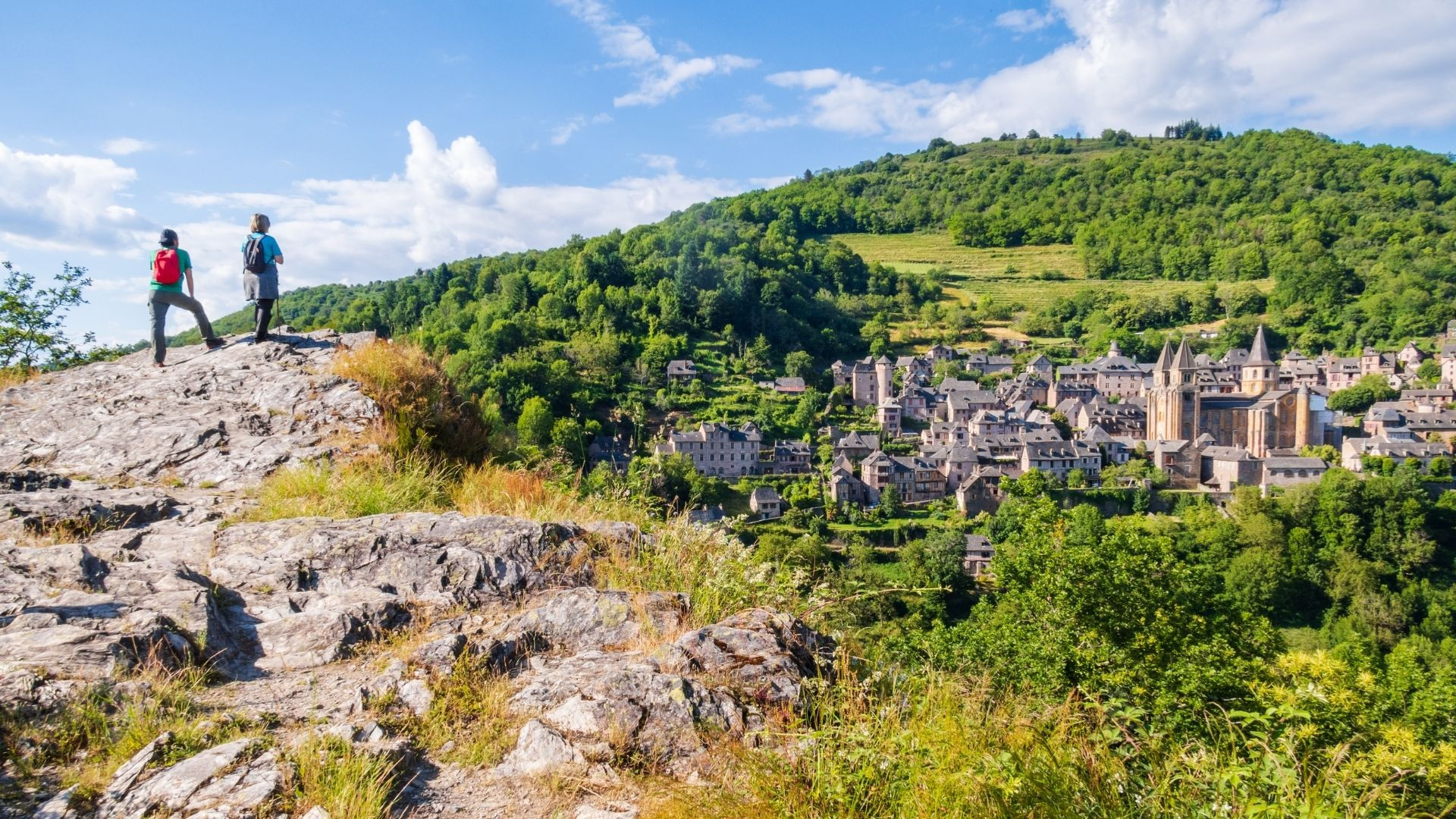 Hikers overlooking the village of Conques - Aveyron - France
