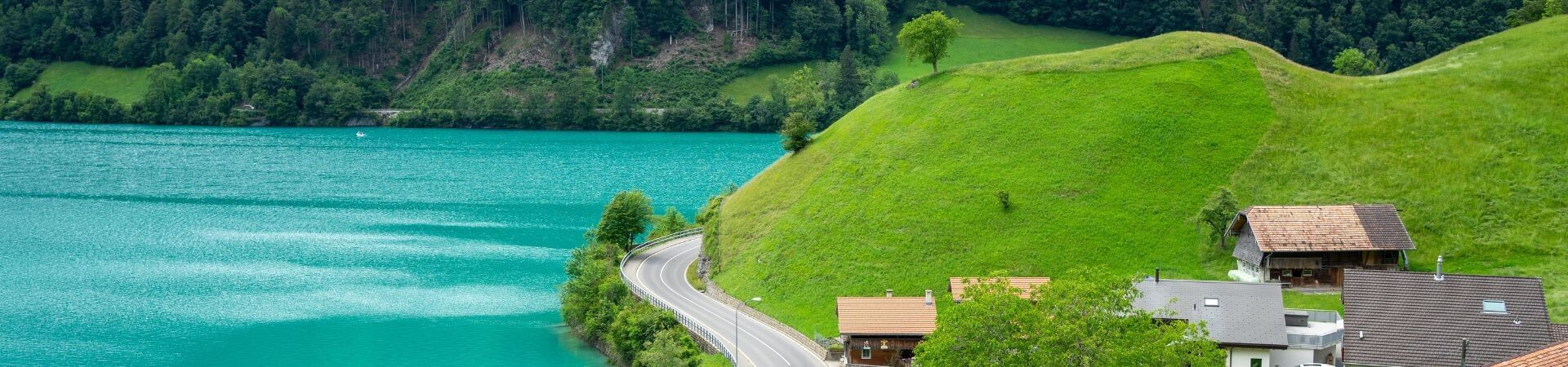 Road along a turquoise lake and green hills - Switzerland