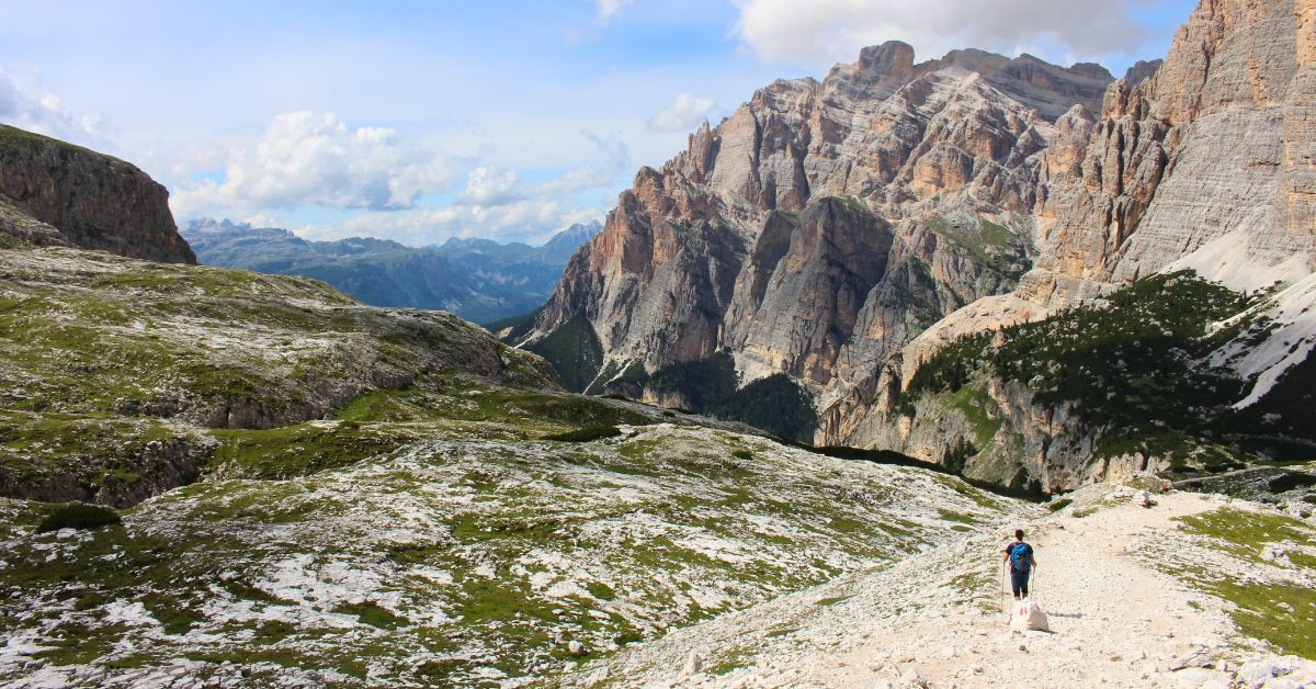 Hiker facing rocky cliffs - Dolomites - Italy