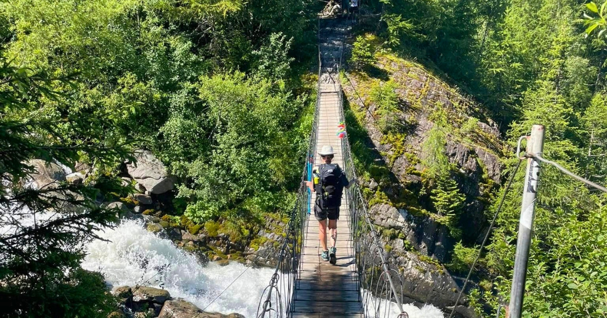 Hiker on a suspension bridge over a torrent - Tour du Mont Blanc - Haute-Savoie, France