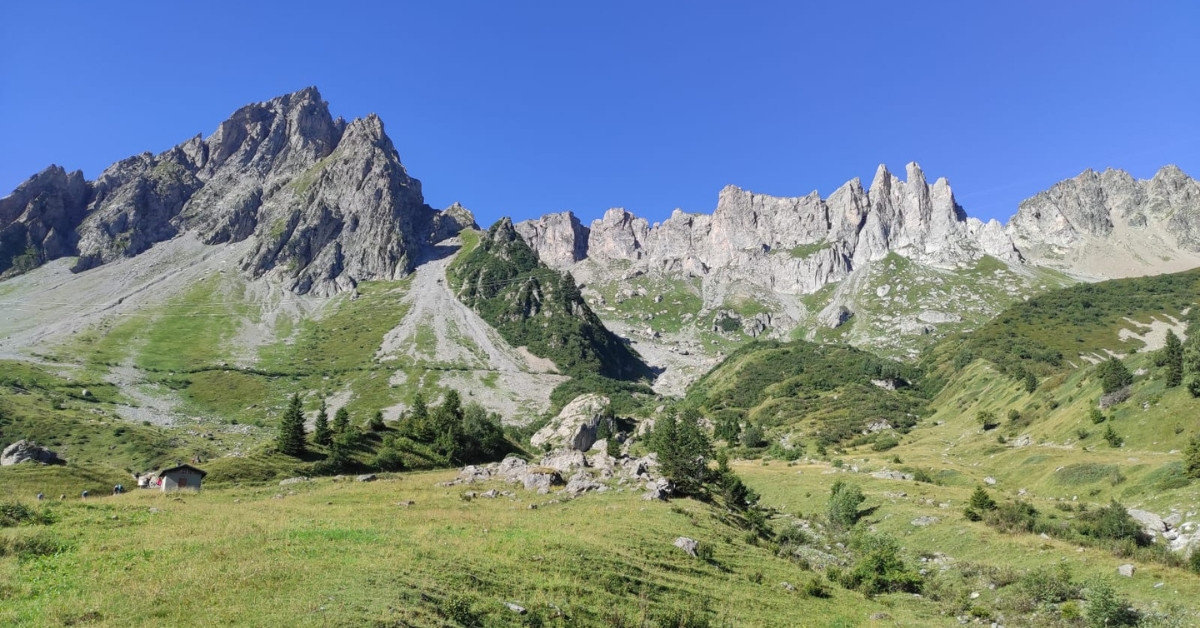 Alpine meadows and rocky spires under blue sky - Tour du Mont-Blanc - France