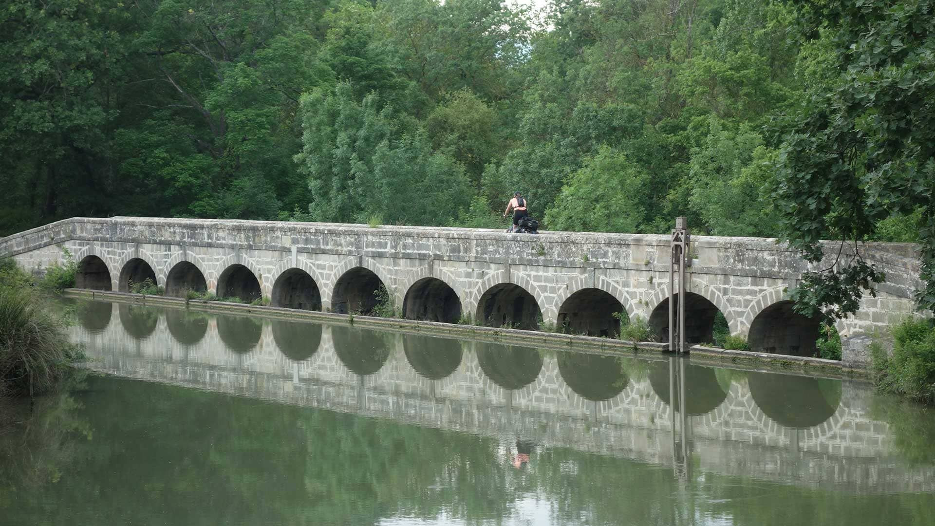 Cyclist on a stone canal bridge - Canal du Midi - France